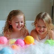Happy children in tub with rainbow bath bombs